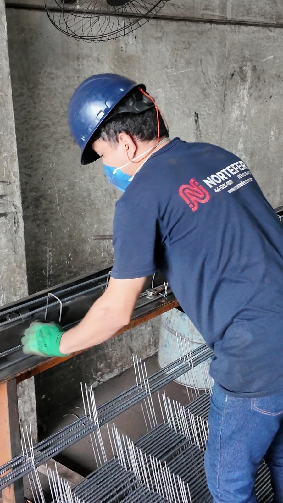 Operador da Nortefer de capacete azul montando armadura sobre o gabarito no galpão em Maringá
