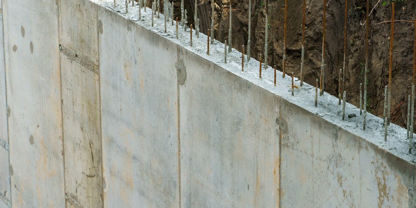 Muro de arrimo de concreto armado com vergalhões de espera no topo e terra atrás
