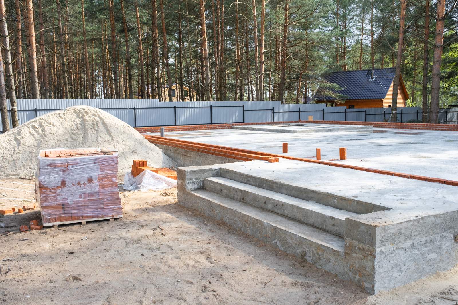 Radier concretado em obra residencial, com a placa de fundação pronta e blocos para a alvenaria ao lado
